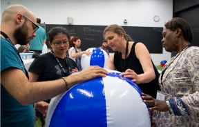 Four people are looking at a blue and white striped beach ball